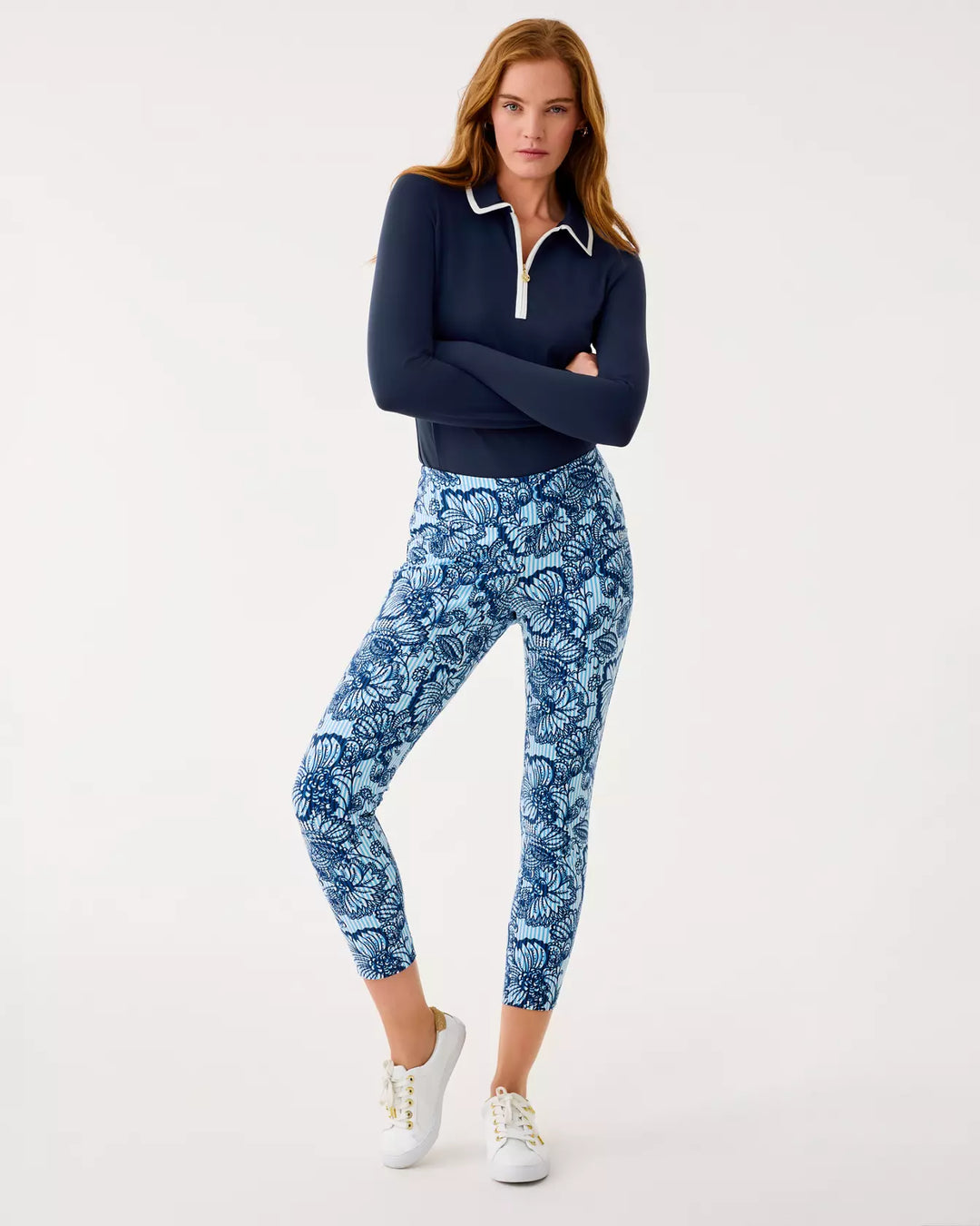 Woman wearing a navy long-sleeve top and blue floral leggings on a white background