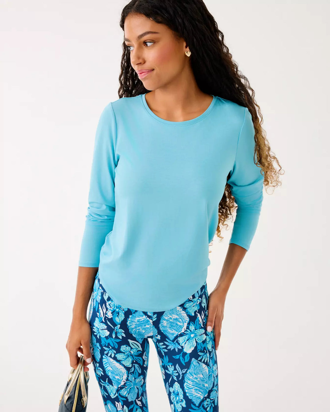Woman wearing a light blue top and floral pants on a white background