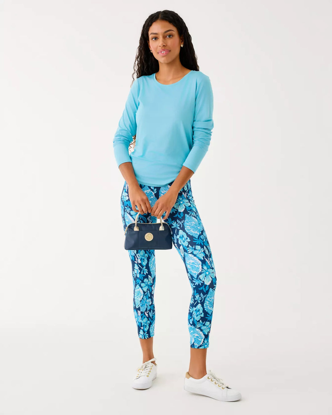 Woman wearing a blue top and floral pants with a white background