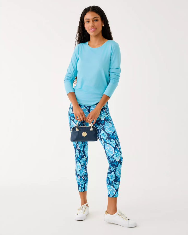 Woman wearing a blue top and floral pants with a white background