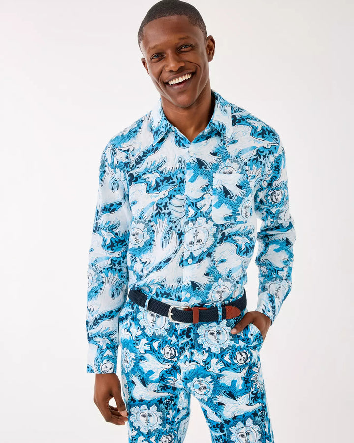 Man wearing a blue patterned shirt and pants on a white background