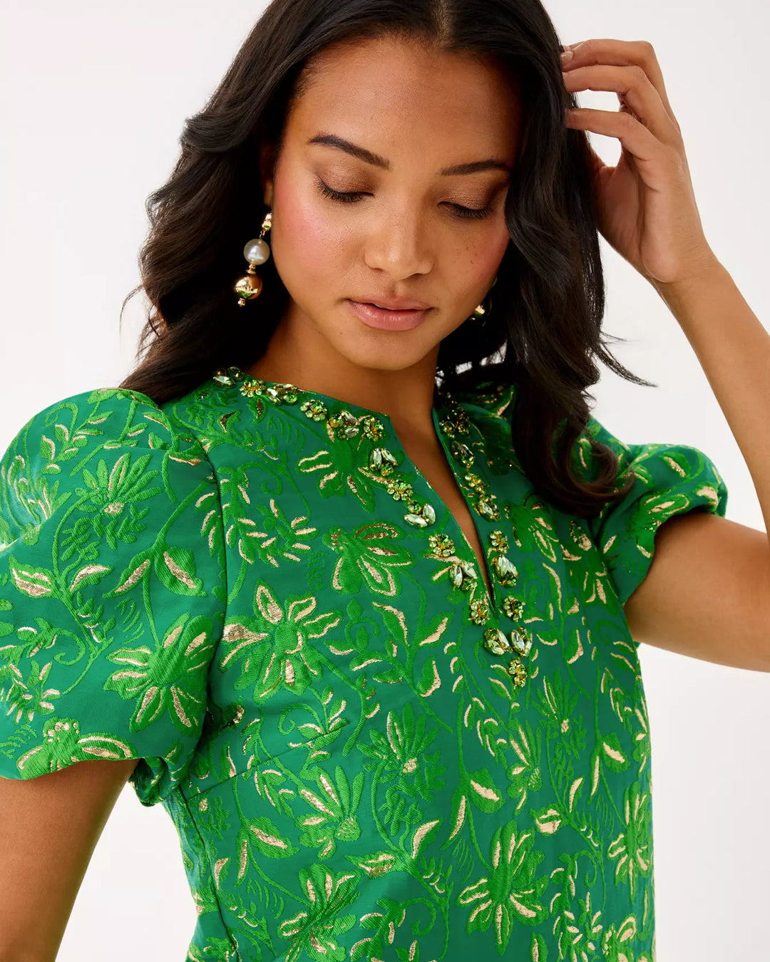Woman wearing a green floral dress with a plain background