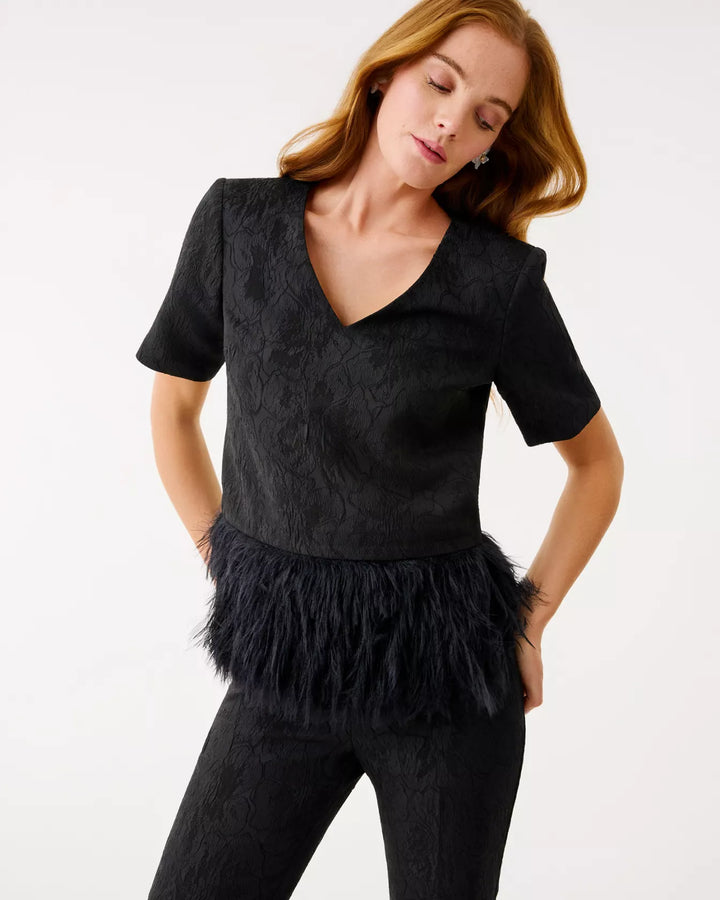 Woman wearing a black top with feather details on a white background