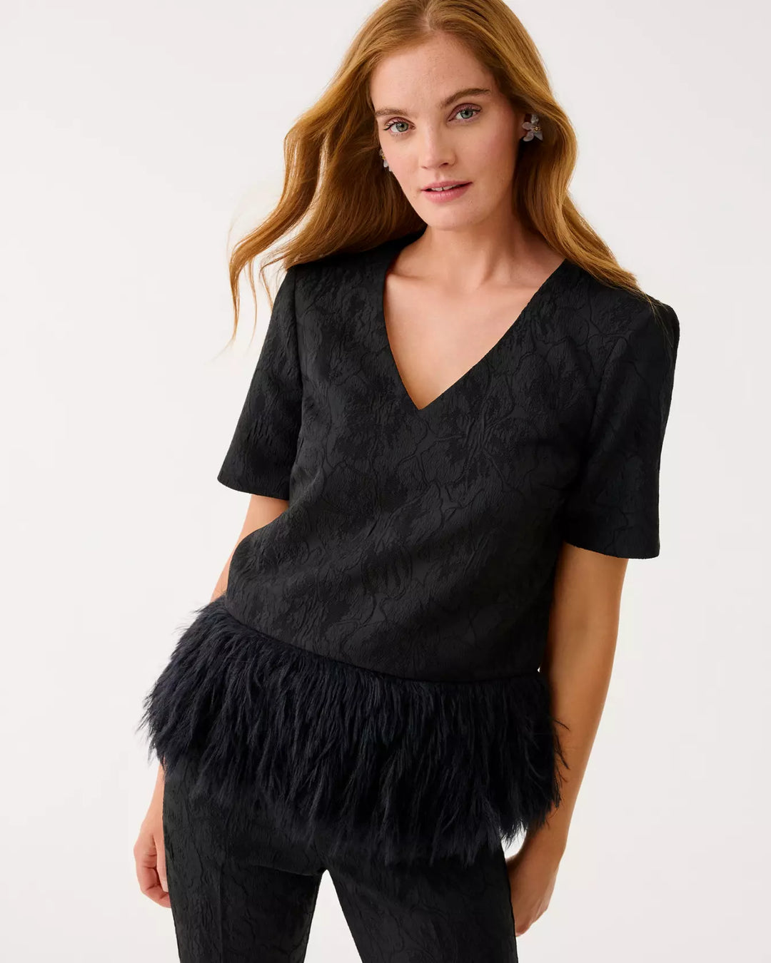 Woman wearing a black top with feather details on a white background