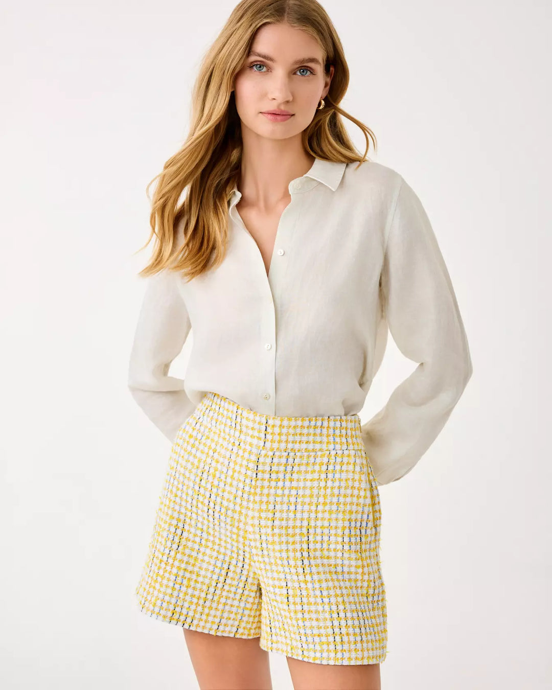Woman wearing a white shirt and yellow checkered shorts on a white background