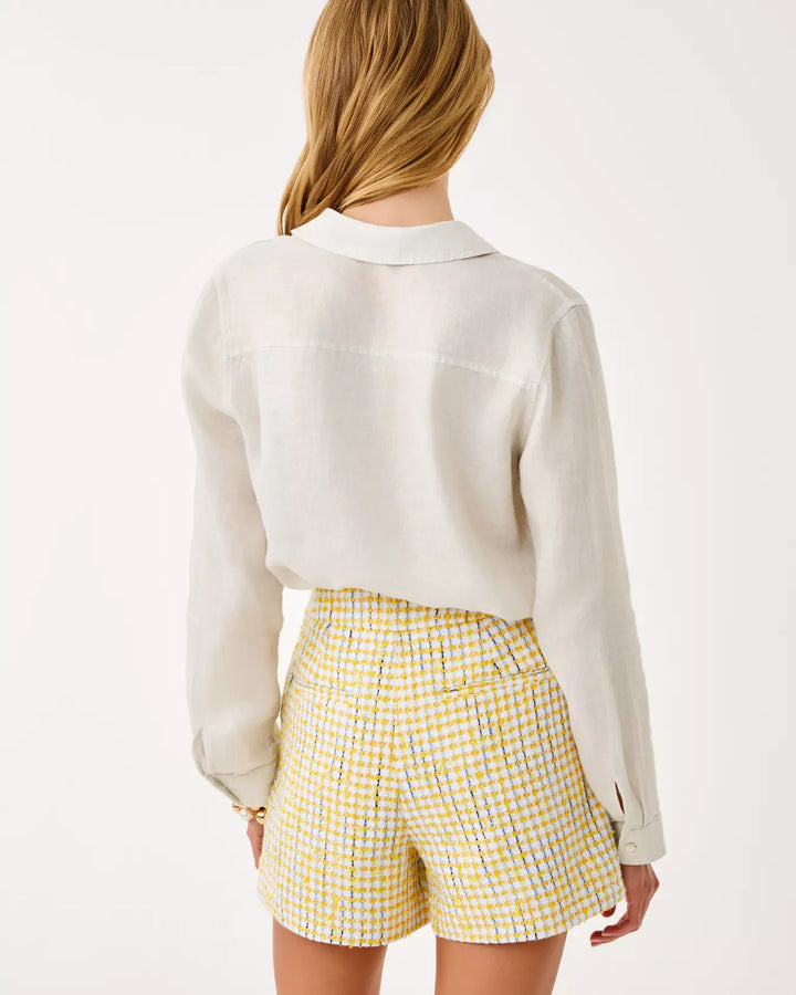 Person wearing a white shirt and yellow checkered shorts on a plain background
