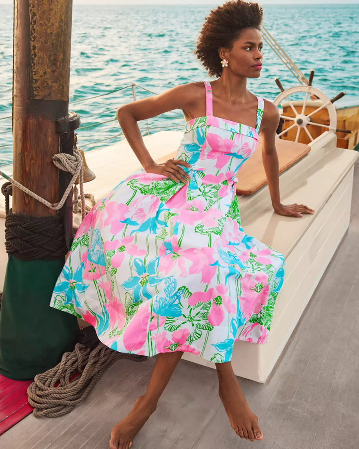 Woman in a colorful floral dress sitting on a boat with ocean in the background