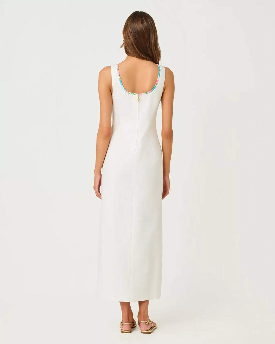 The back of a woman wearing a white sleeveless dress on a plain background